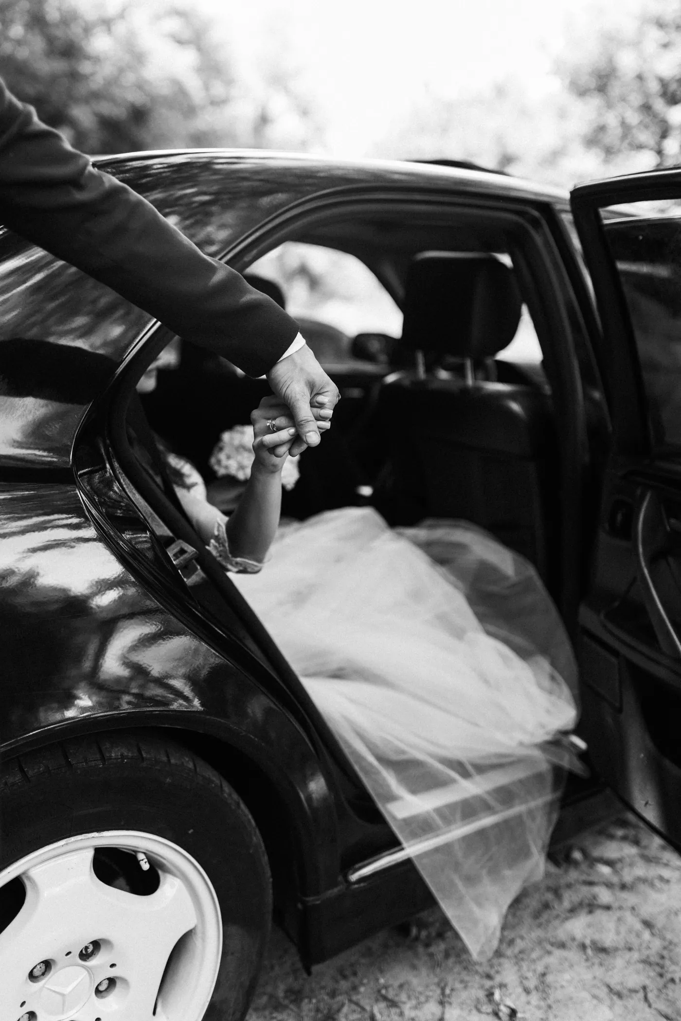 Formal wedding transportation moment beside a luxury car